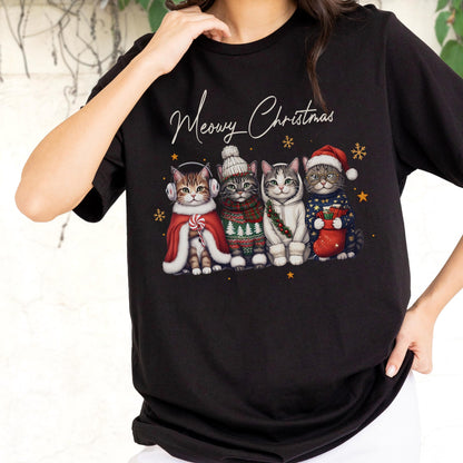 May include: A black t-shirt featuring a graphic of four cats dressed in winter holiday attire with the text Meowy Christmas above them. The cats wear items including earmuffs, a knit hat, a scarf, a hoodie, and a Santa hat with a stocking.