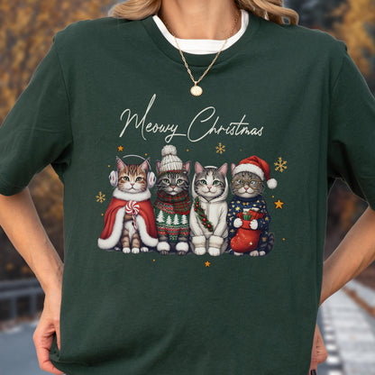 May include: A dark green short-sleeve t-shirt featuring a graphic of four cats dressed in winter clothing with the text Meowy Christmas. The cats wear items including earmuffs, a knit hat, a hoodie, and a Santa hat, surrounded by gold stars.