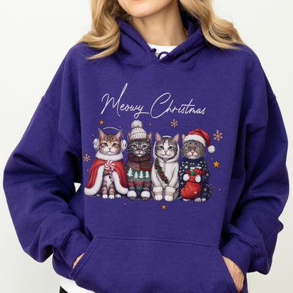 May include: A deep purple hooded sweatshirt featuring a graphic of four cats dressed in winter attire with the text Meowy Christmas. The cats wear items including earmuffs, a knit hat, a scarf, and a Santa hat, surrounded by small gold stars.