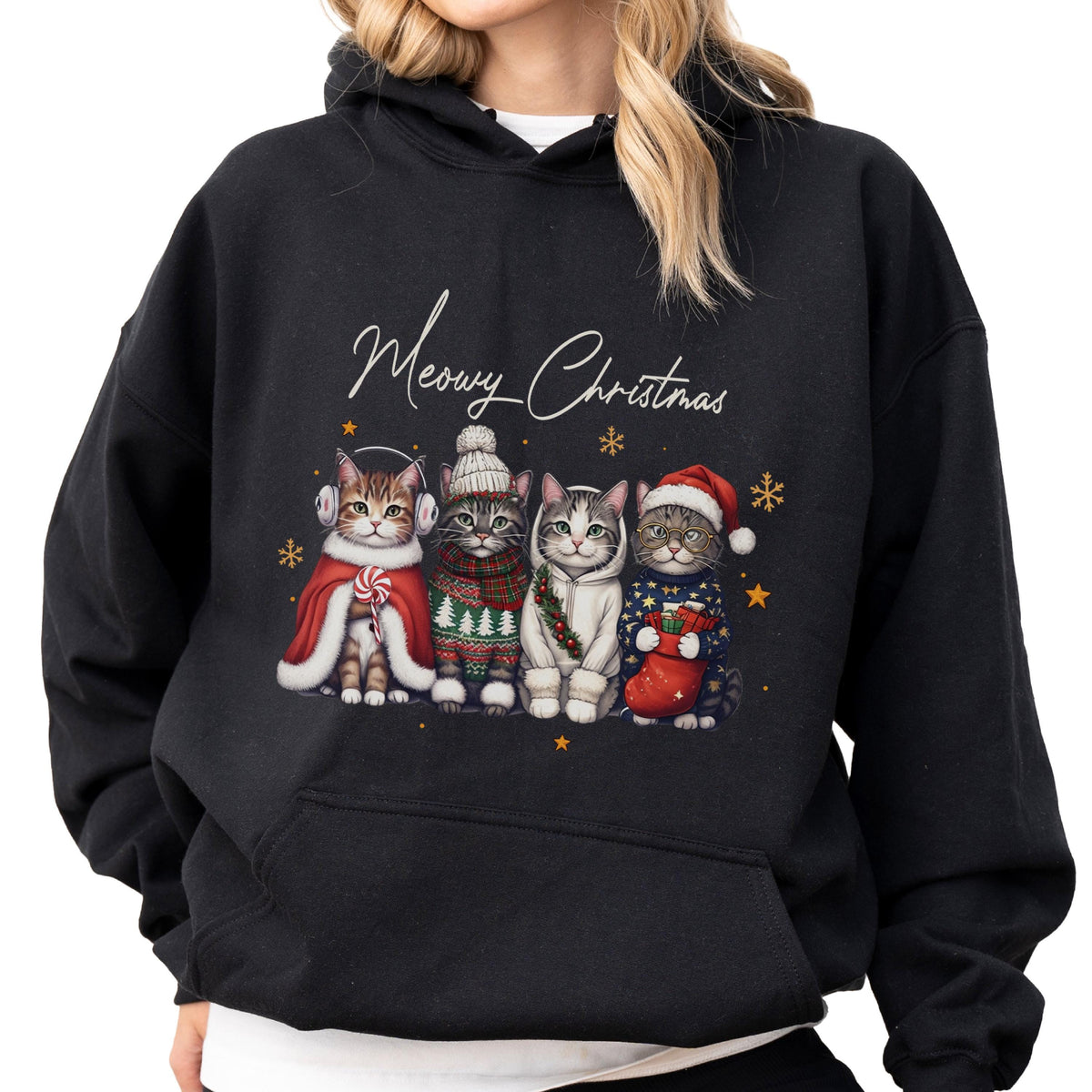 May include: A black hooded sweatshirt featuring a graphic of four cats dressed in winter attire with the text Meowy Christmas. The cats wear accessories including earmuffs, a knit hat, a scarf, a hoodie, and a Santa hat, surrounded by snowflakes.