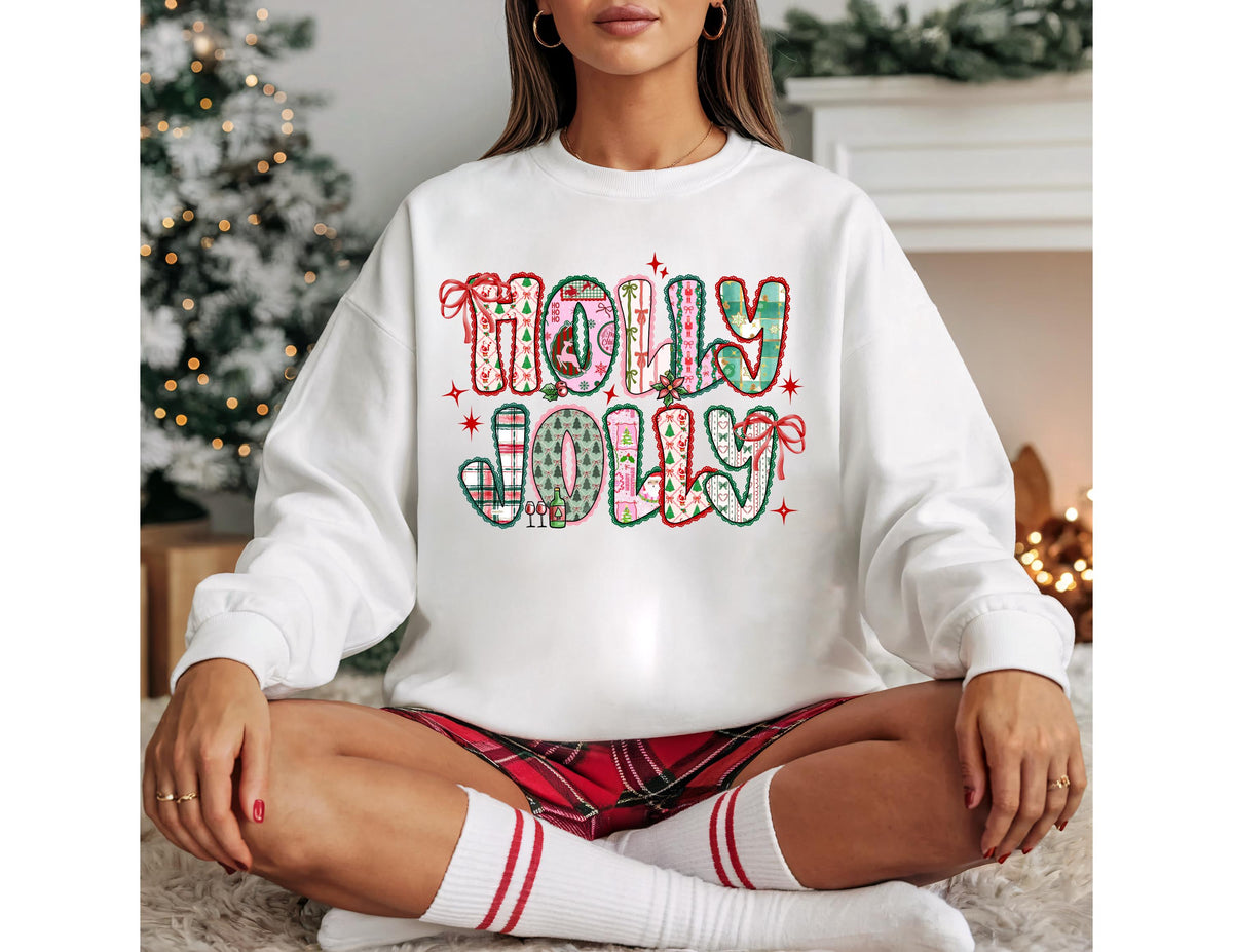 May include: White sweatshirt with the words "HOLLY JOLLY" in a colorful, festive design. The text features a mix of patterns, including plaid and floral, with red and green accents. The sweatshirt is a cozy, long-sleeved garment.
