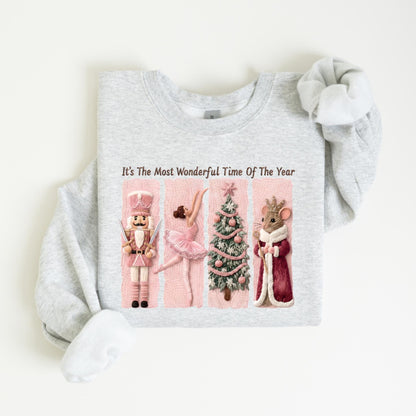 May include: A light gray sweatshirt with the text "It's The Most Wonderful Time Of The Year." The graphic features a nutcracker, ballerina, Christmas tree, and mouse in a red coat, all on pink panels.