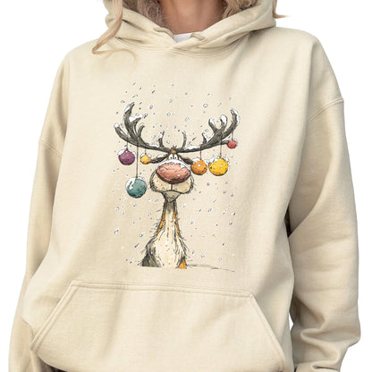 May include: A beige hooded sweatshirt featuring a graphic illustration of a reindeer with large antlers decorated with colorful hanging ornaments. The reindeer has a prominent pink nose and is depicted amidst falling snow in a cartoon style.