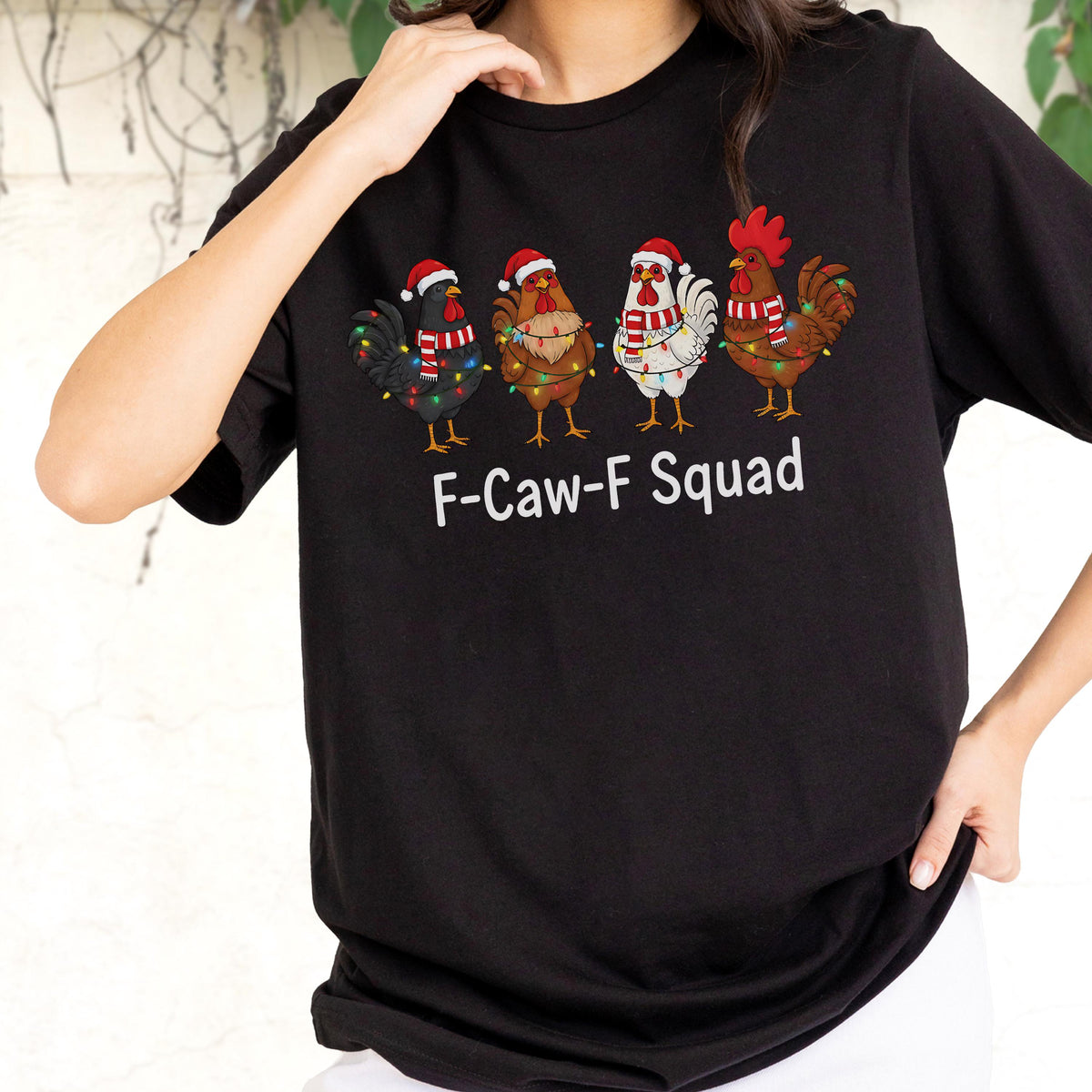 May include: Black t-shirt featuring four cartoon chickens wearing Santa hats and Christmas lights. The chickens are in various colors, including black, brown, and white. The text "F-Caw-F Squad" is printed in white below the chickens.