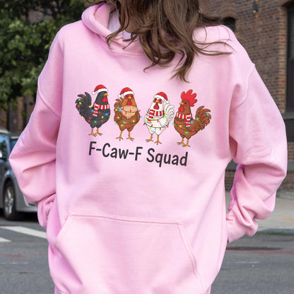 May include: A light pink hoodie featuring a graphic of four cartoon roosters wearing Santa hats and Christmas lights. The text "F-Caw-F Squad" is printed below the roosters. The hoodie has a front pocket and a hood.