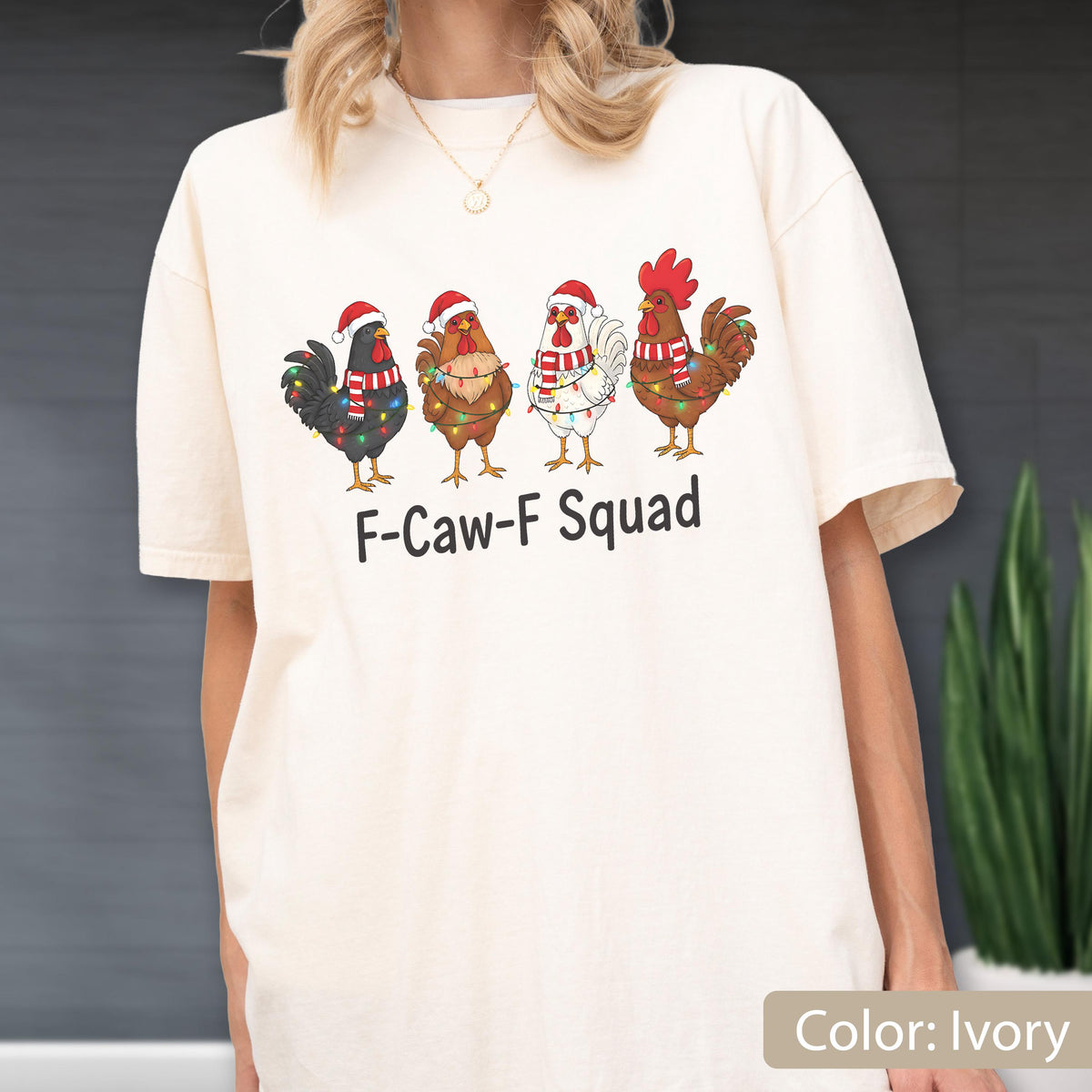 May include: Ivory-colored t-shirt featuring a graphic of four cartoon roosters wearing Santa hats and Christmas lights. The text "F-Caw-F Squad" is printed below the roosters. The shirt has a relaxed fit.