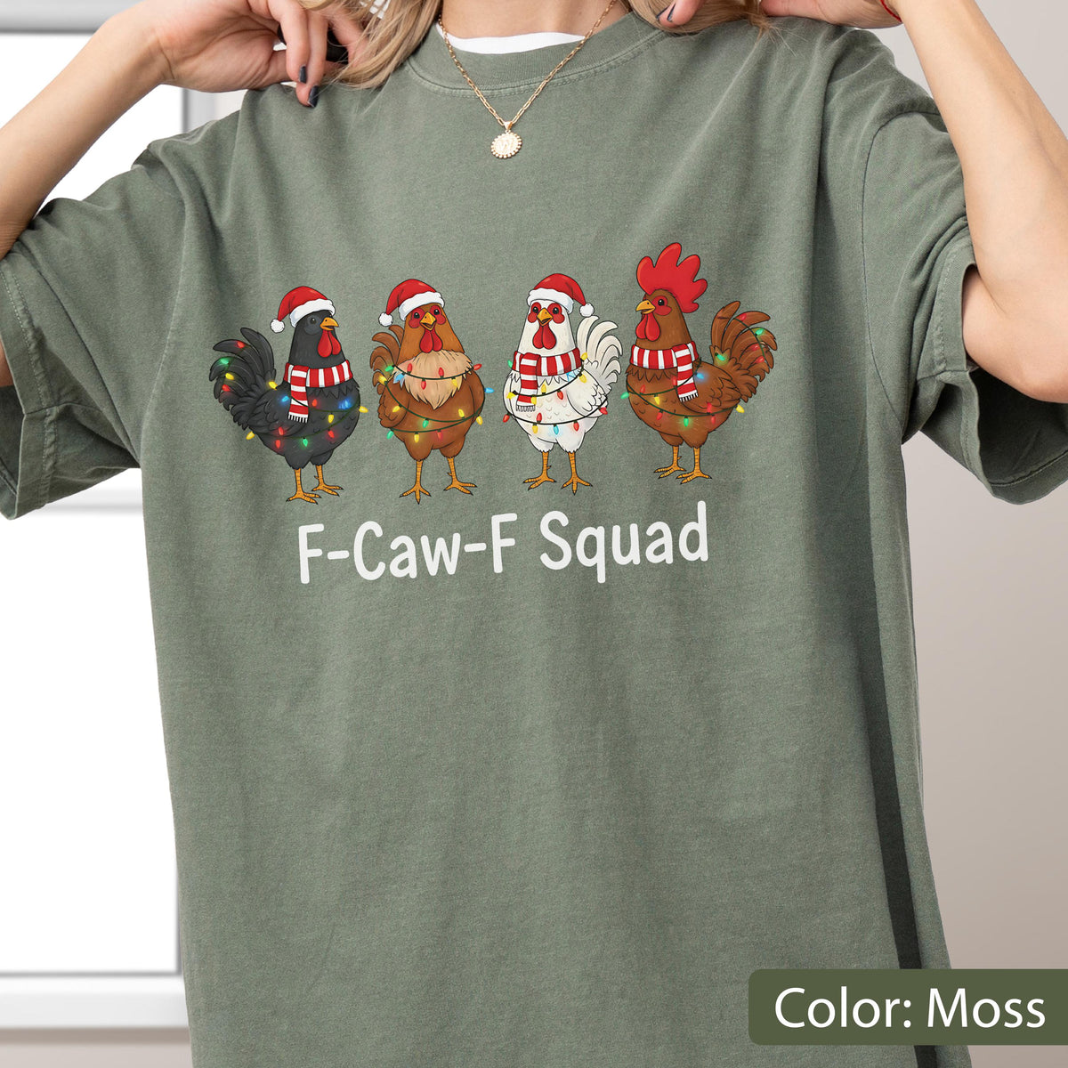 May include: Moss green t-shirt featuring four cartoon roosters wearing Santa hats and scarves, adorned with Christmas lights. The text "F-Caw-F Squad" is printed below the roosters. The shirt is a solid color.
