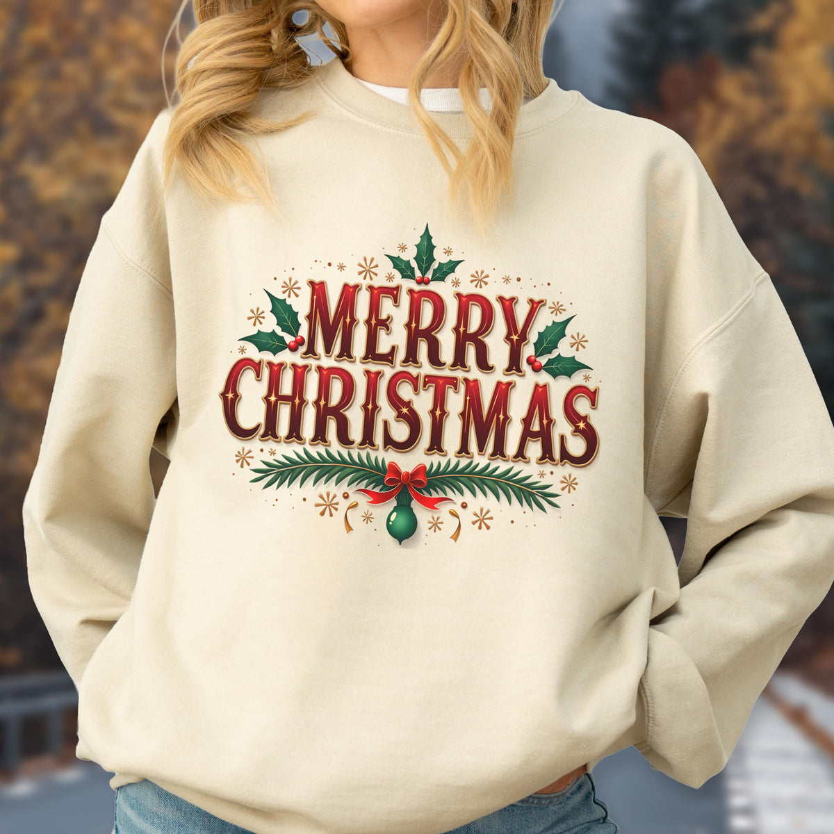 May include: A cream-colored sweatshirt with the words "MERRY CHRISTMAS" in red, with green holly leaves and a green ornament. The design is surrounded by small stars.