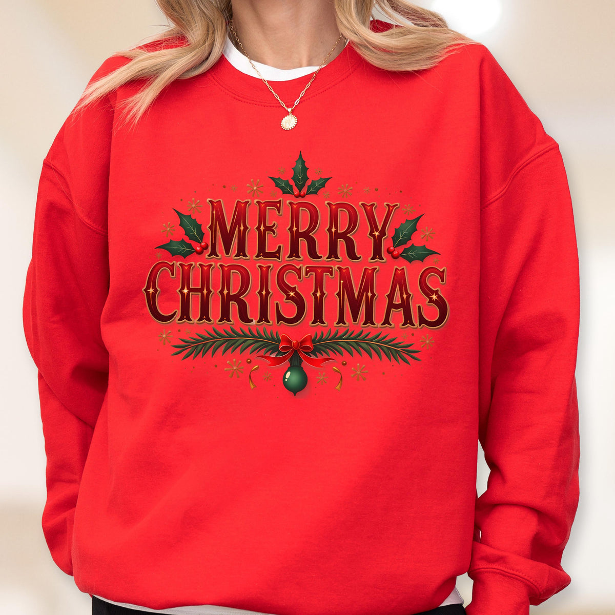 May include: A red sweatshirt with the words "MERRY CHRISTMAS" in a decorative font. The text is accented with green holly leaves, a red bow, and a green ornament. The sweatshirt is a festive holiday garment.