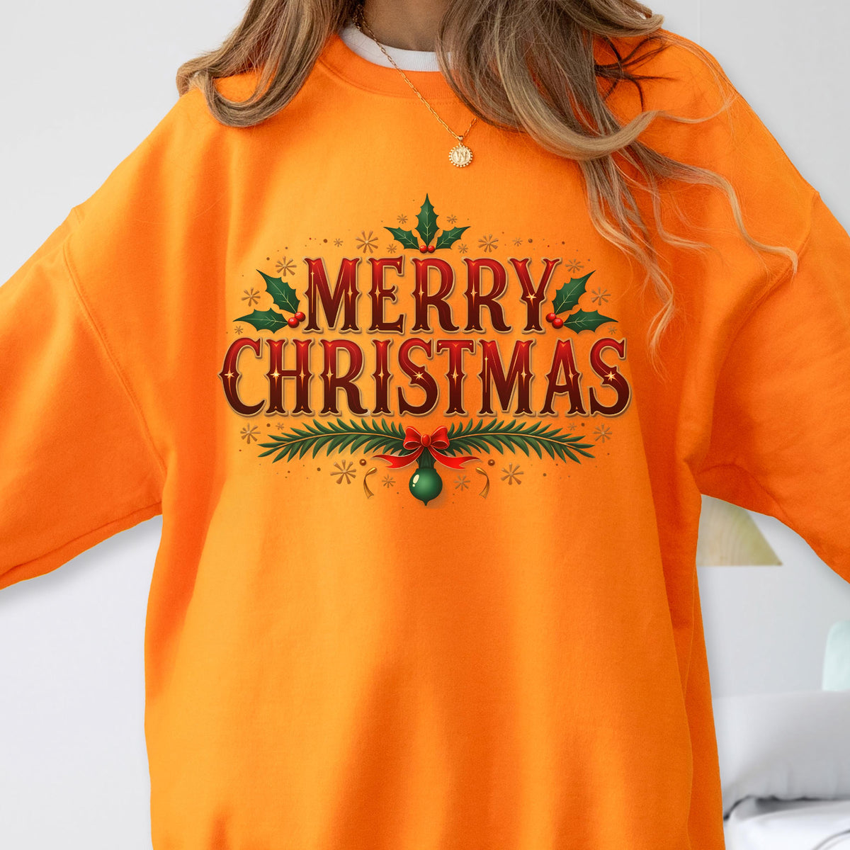 May include: Bright orange sweatshirt with the text "MERRY CHRISTMAS" in a festive design. The text is in red and green with decorative holly and a green ornament. The sweatshirt is a solid color and has a crew neck.