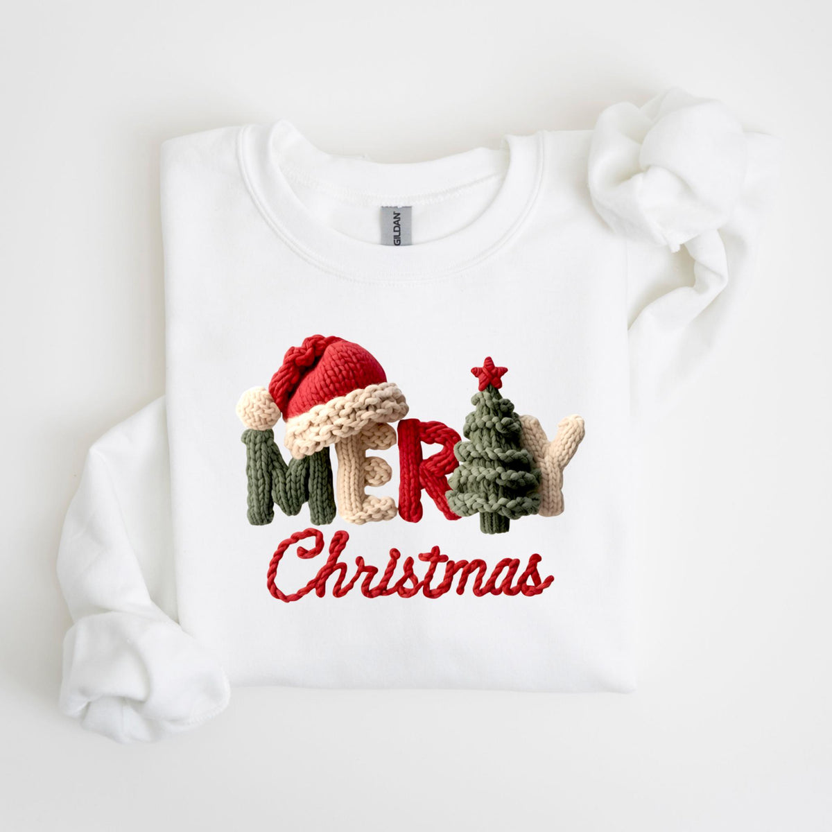 May include: White sweatshirt with a knitted design that spells out "MERRY Christmas". The design includes a Santa hat, Christmas tree, and the word "MERRY" in green, beige, and red. The word "Christmas" is in red.