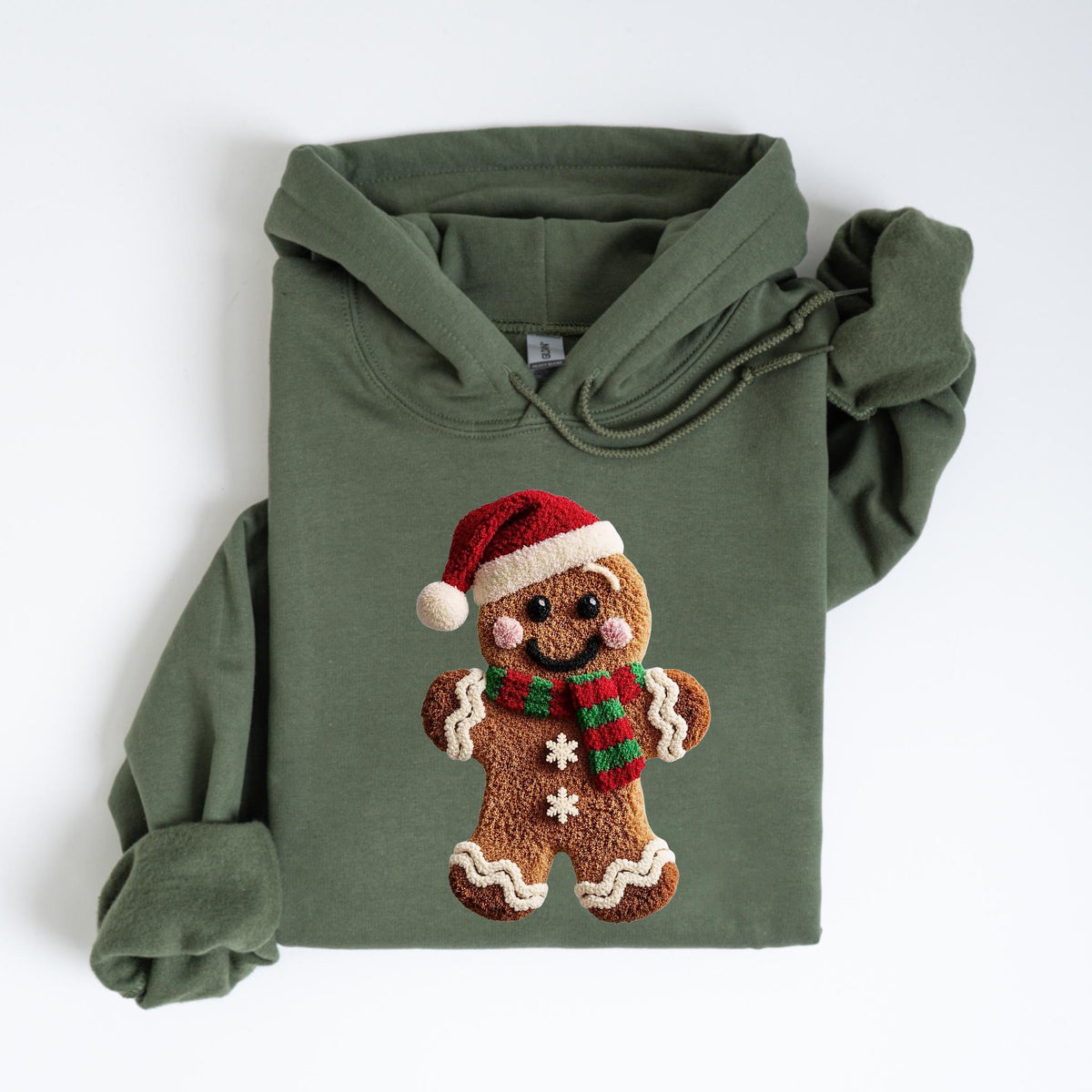 May include: An olive green hooded sweatshirt featuring a gingerbread man design. The gingerbread man wears a red Santa hat and a red and green scarf. The design is centered on the front of the sweatshirt.