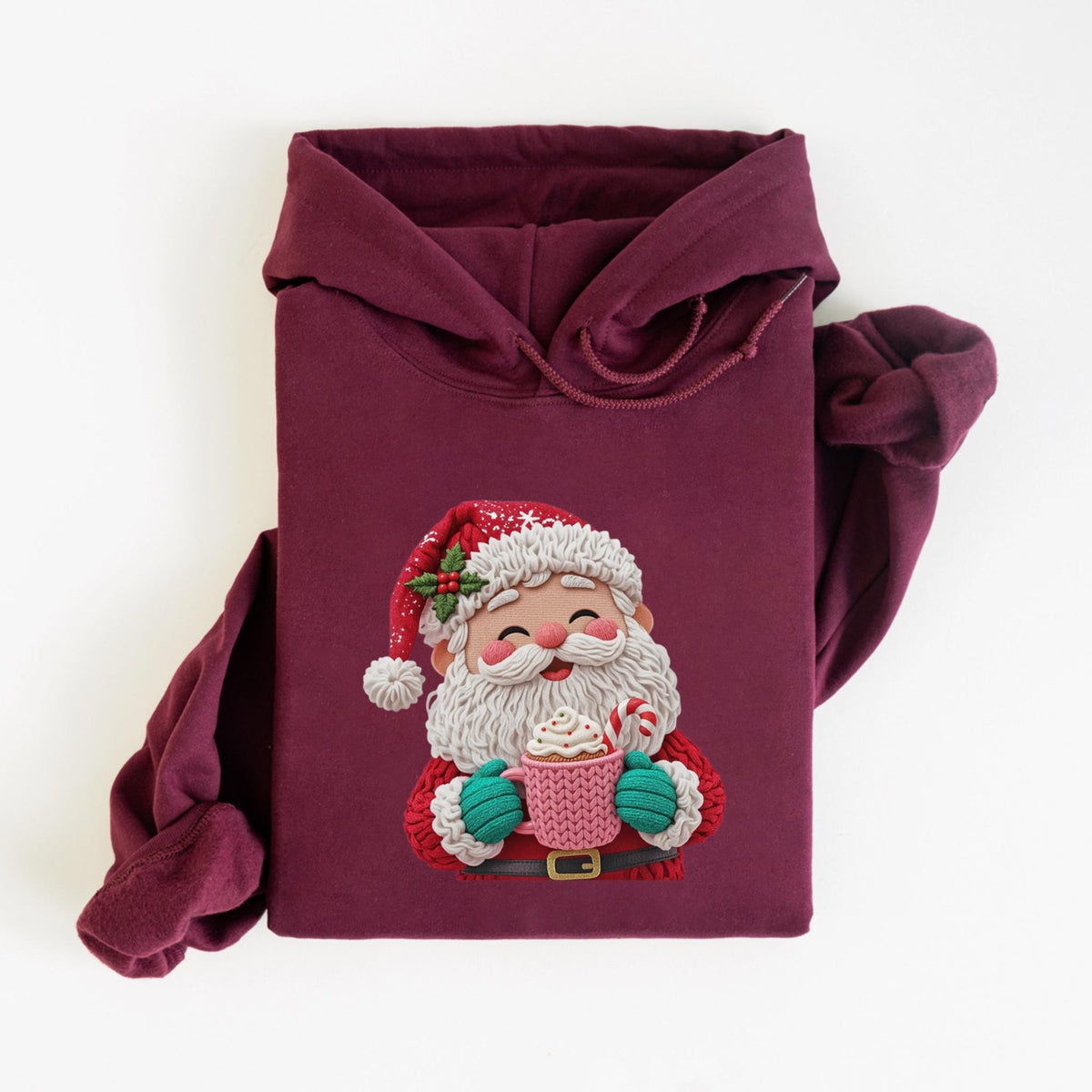 May include: Burgundy hoodie featuring a festive Santa Claus graphic. The Santa illustration includes a red hat with holly, a white beard, and a pink mug with whipped cream and a candy cane. The hoodie has a drawstring hood and long sleeves.