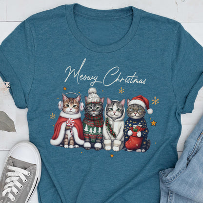 May include: A teal crew neck t-shirt featuring a graphic of four cats wearing winter accessories and the text Meowy Christmas. The cats are dressed in a red cape with earmuffs, a knit hat and sweater, a white hoodie with a wreath, and a Santa hat.