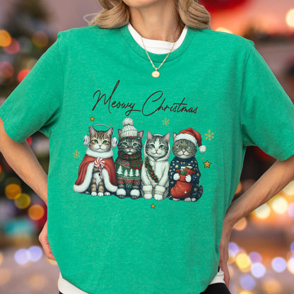 May include: A bright green short-sleeve t-shirt featuring a graphic of four cats wearing winter accessories and the text Meowy Christmas. The cats are dressed in a red cape with earmuffs, a knit sweater and hat, a white hoodie, and a holiday sweater with a stocking.