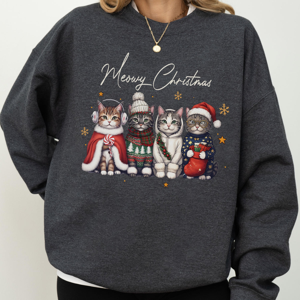 May include: A dark charcoal gray crewneck sweatshirt featuring the white cursive text Meowy Christmas above a graphic of four cats. The cats are wearing winter accessories including earmuffs, a knit hat, a scarf, a hoodie, and a Santa hat.