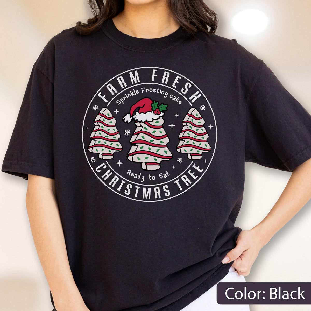 May include: A black t-shirt featuring a circular graphic with the text FARM FRESH CHRISTMAS TREE, Sprinkle Frosting cake, and Ready to Eat. The design includes three white cake slices shaped like Christmas trees with red and green sprinkles.