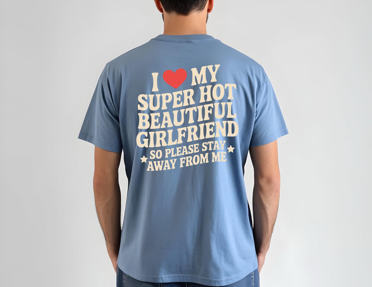 May include: A blue t-shirt with the text "I ❤️ MY SUPER HOT BEAUTIFUL GIRLFRIEND SO PLEASE STAY AWAY FROM ME" in white and a red heart graphic. The shirt is made of a soft material and has short sleeves.
