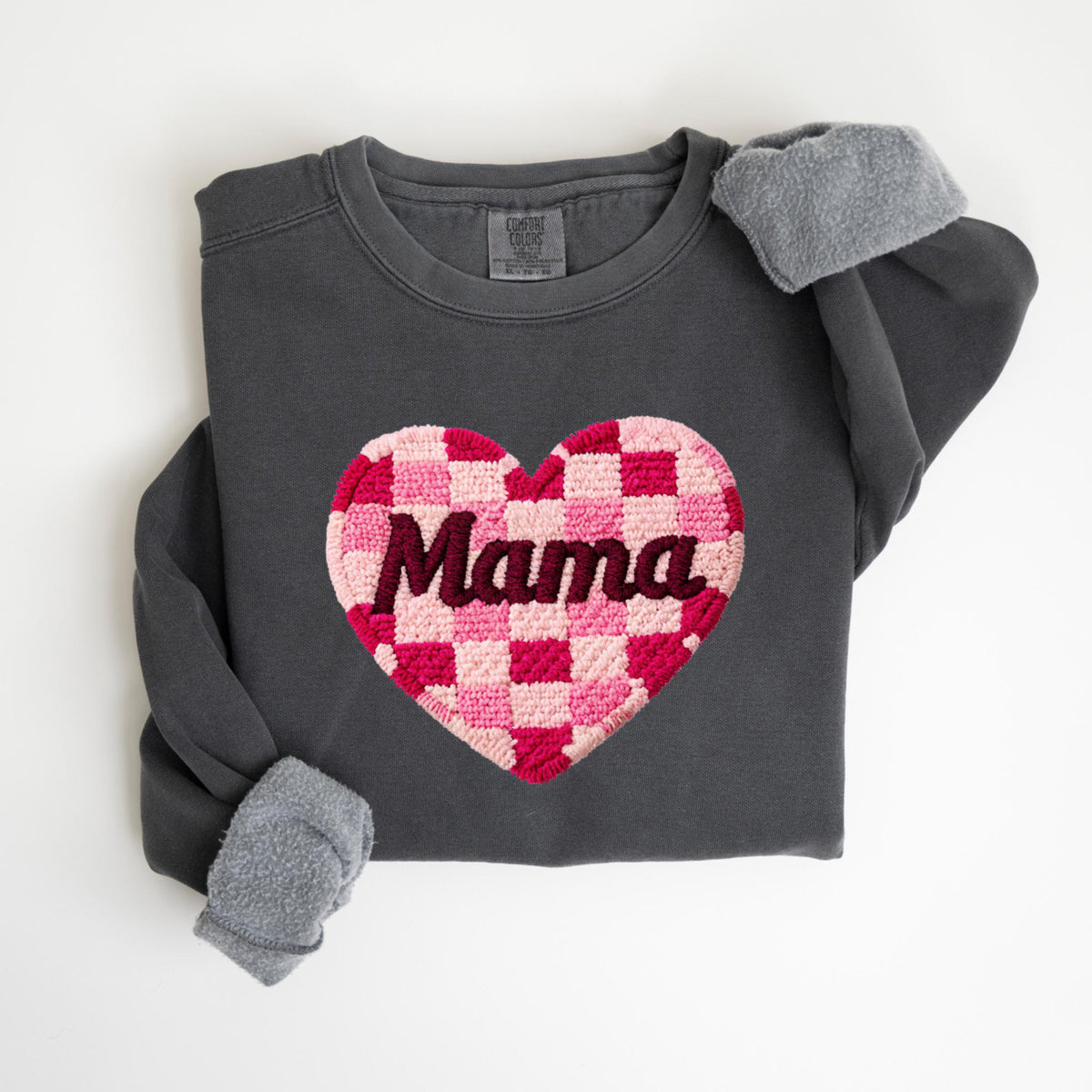 May include: Dark gray sweatshirt with a large, checkered heart design in shades of pink and red. The word "Mama" is embroidered across the heart. The sleeves have gray, fuzzy cuffs.