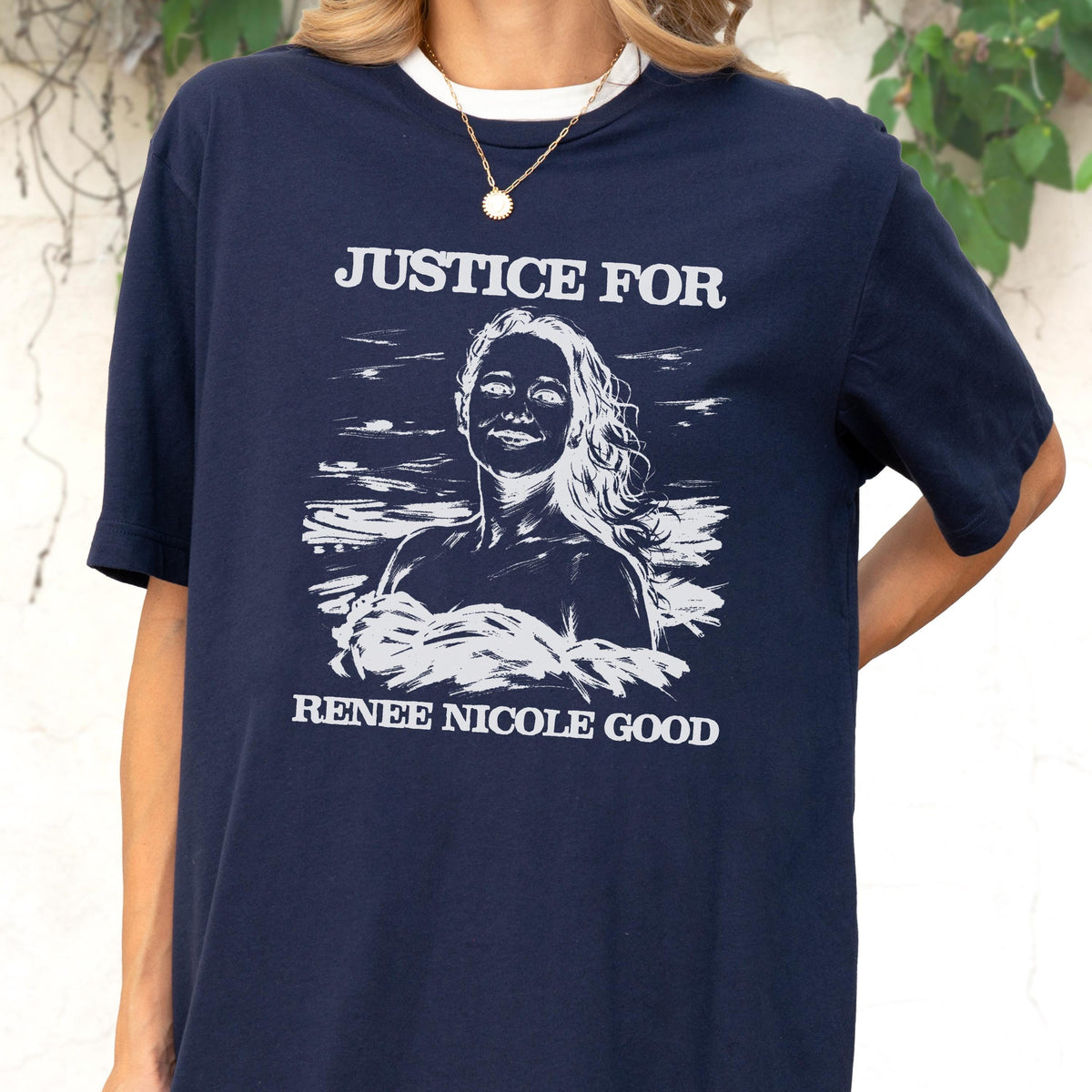 May include: Navy blue t-shirt with a white collar and the text "JUSTICE FOR" above a white illustration of a woman. Below the illustration is the text "RENEE NICOLE GOOD".