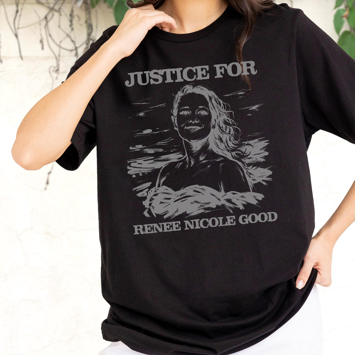 May include: Black t-shirt with a gray graphic of a woman and the text "JUSTICE FOR RENEE NICOLE GOOD". The graphic is a stylized portrait with flowing hair. The shirt is a crew neck.