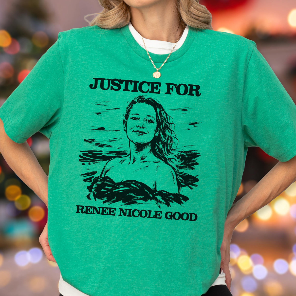 May include: Green t-shirt with the text "JUSTICE FOR" above a black and white portrait of a woman. Below the portrait, the text reads "RENEE NICOLE GOOD". The shirt has short sleeves and a crew neck.