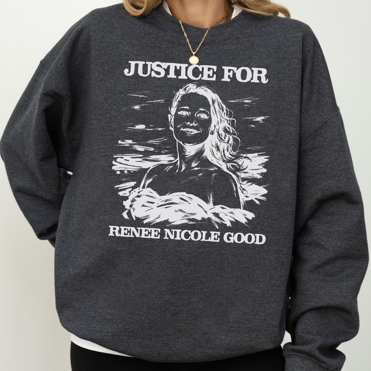 May include: Dark gray sweatshirt with the text "JUSTICE FOR" above a white illustration of a woman, and the text "RENEE NICOLE GOOD" below. The sweatshirt is a crew neck style.