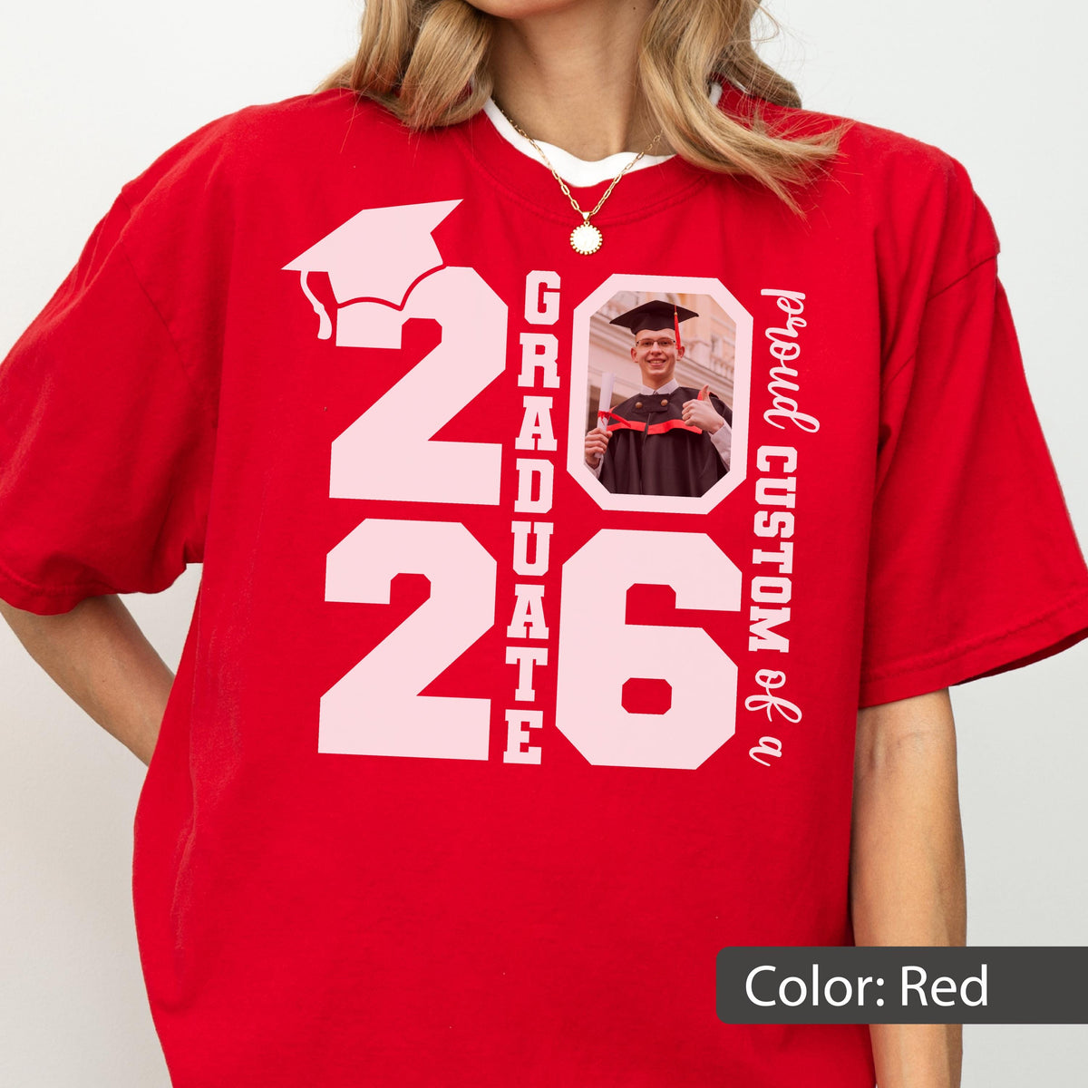 May include: Red t-shirt with a white graphic design for the graduating class of 2026. The design includes a graduation cap, the word "GRADUATE", the number "26", and a photo of a graduate. The text "proud CUSTOM of a" is also included.
