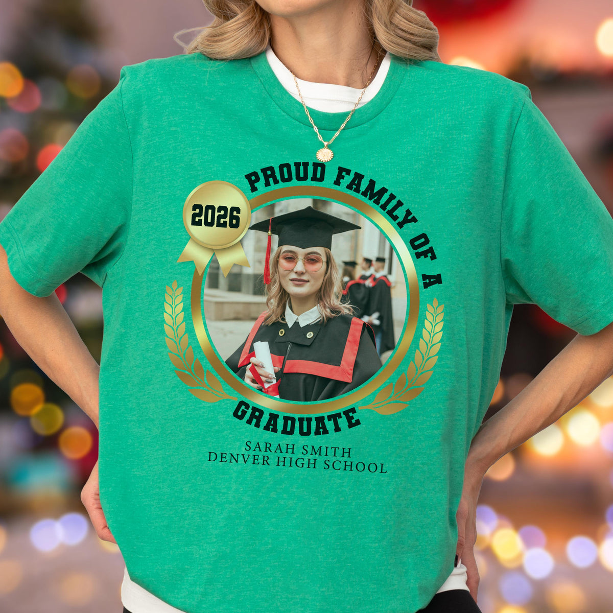 May include: Green t-shirt with a graduation theme. The shirt features a circular design with the words "Proud Family of a Graduate" and a photo of a graduate. The text "2026" is also present.