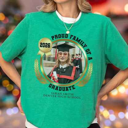 May include: Green t-shirt with a graduation theme. The shirt features a circular design with the words "Proud Family of a Graduate" and a photo of a graduate. The text "2026" is also present.