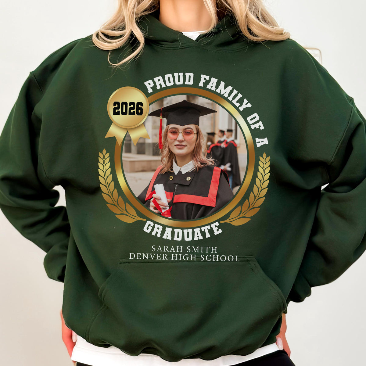 May include: Dark green hooded sweatshirt with a gold emblem featuring a graduate's photo, the text "Proud Family of a Graduate," and the year "2026." The graduate's name and high school are also displayed.