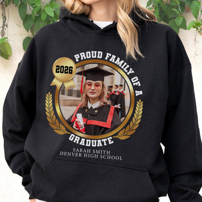 May include: Black hooded sweatshirt with a gold laurel wreath design. The design includes a photo of a graduate, the text "PROUD FAMILY OF A GRADUATE", the year "2026", and the graduate's name and high school.
