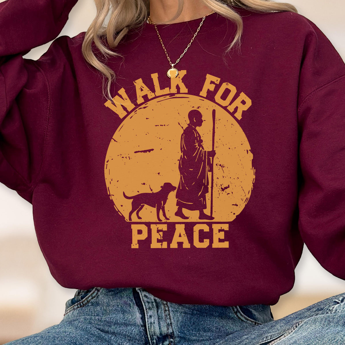 May include: Burgundy sweatshirt with a circular graphic featuring a person with a dog, walking with a staff. The graphic is in shades of yellow and brown, with the words "WALK FOR PEACE" in a circular arrangement.