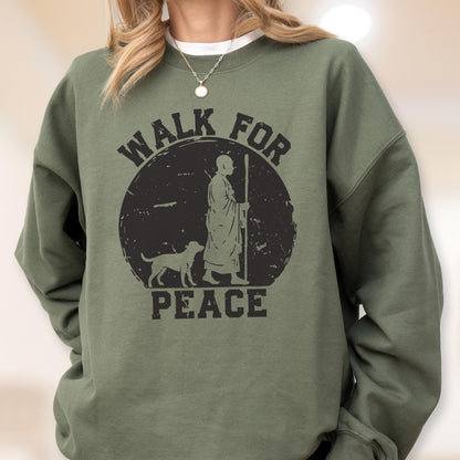 May include: Olive green sweatshirt with a black graphic. The graphic features a figure with a staff, a dog, and the words "WALK FOR PEACE" in a circular design. The sweatshirt has long sleeves and a crew neck.