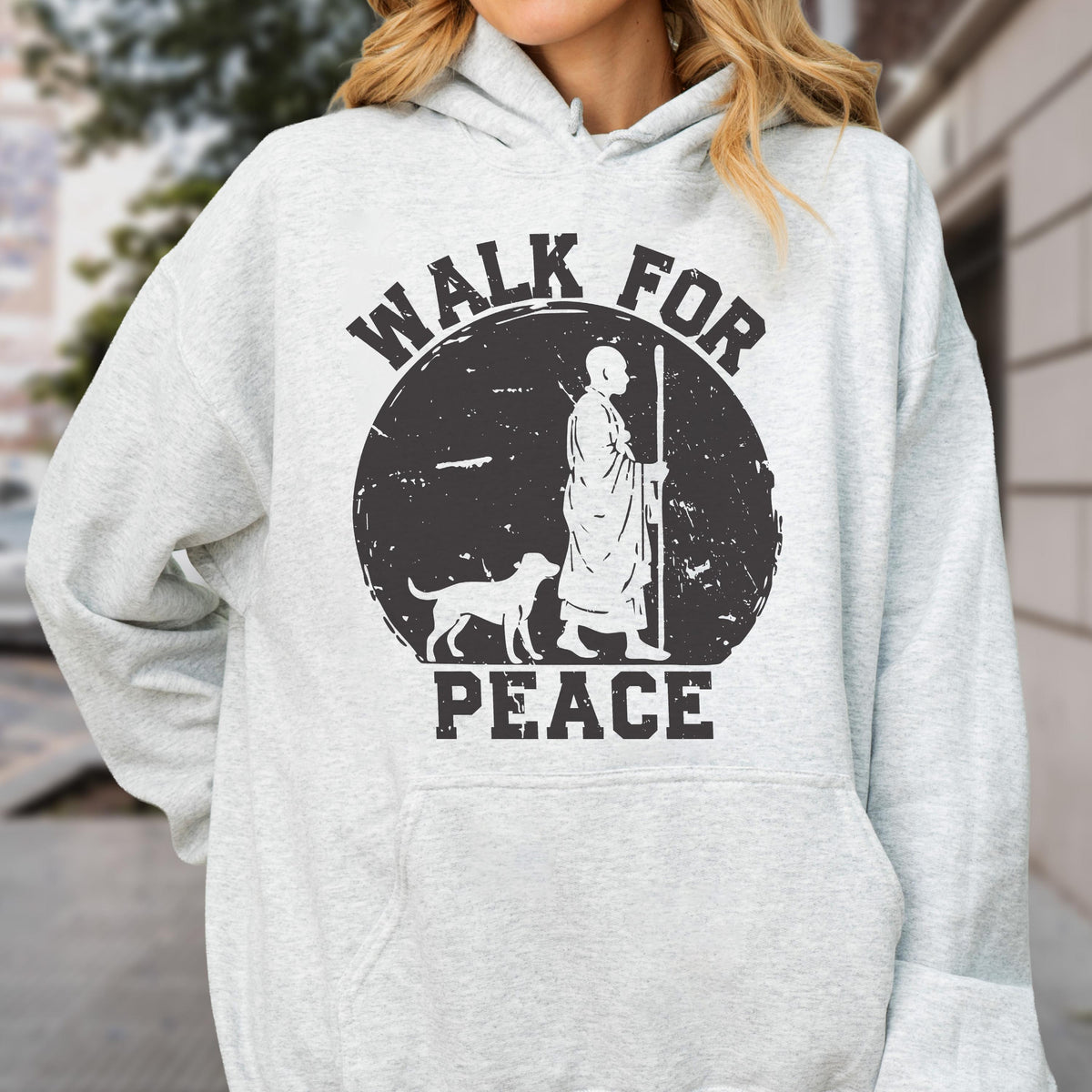 May include: Light gray hoodie with a black graphic. The graphic features a figure with a dog and the words "WALK FOR PEACE" in a circular design. The hoodie has a drawstring hood and a front pocket.