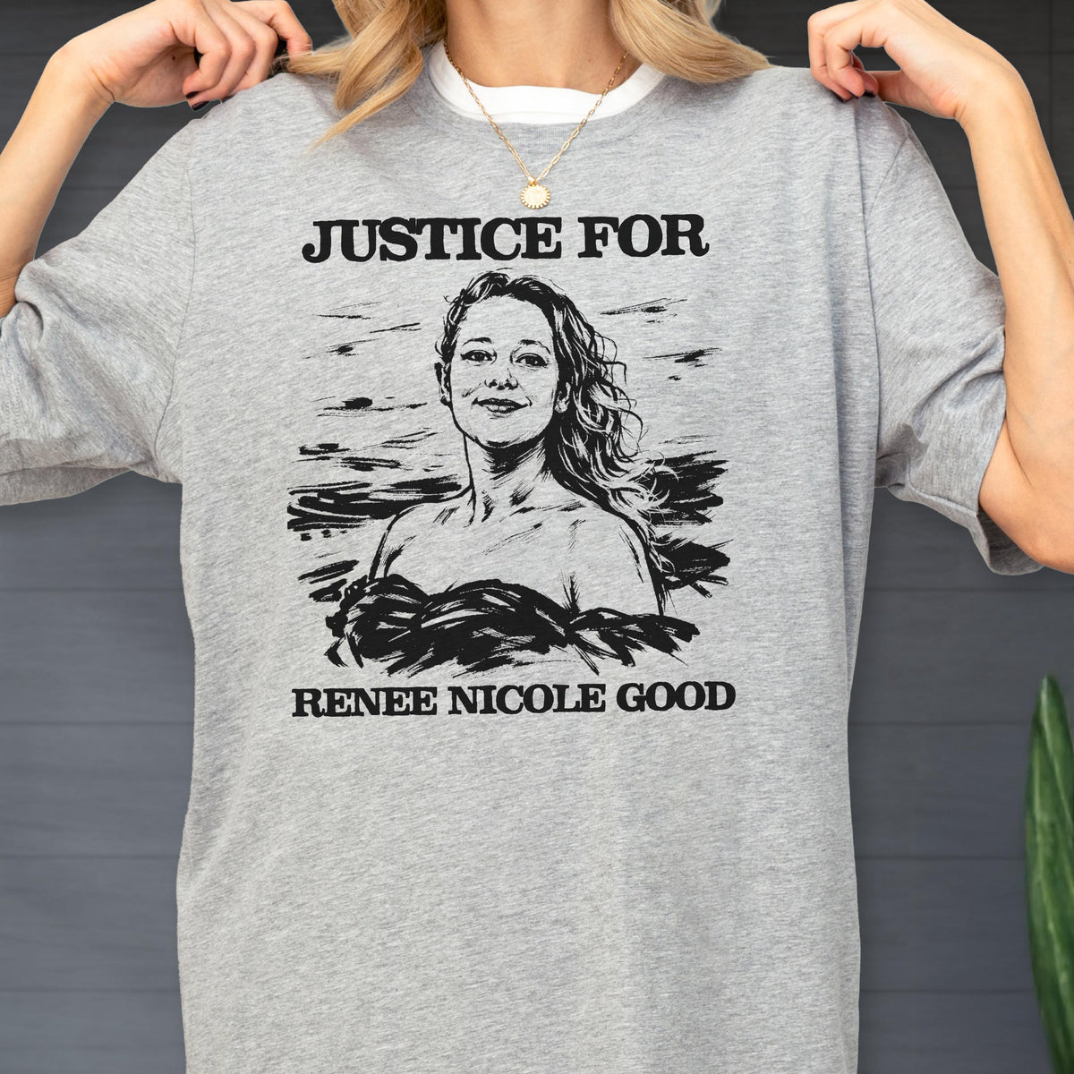 May include: A gray sweatshirt with the words "JUSTICE FOR" above a black and white illustration of a woman. Below the illustration is the text "RENEE NICOLE GOOD". The sweatshirt has a crew neck.