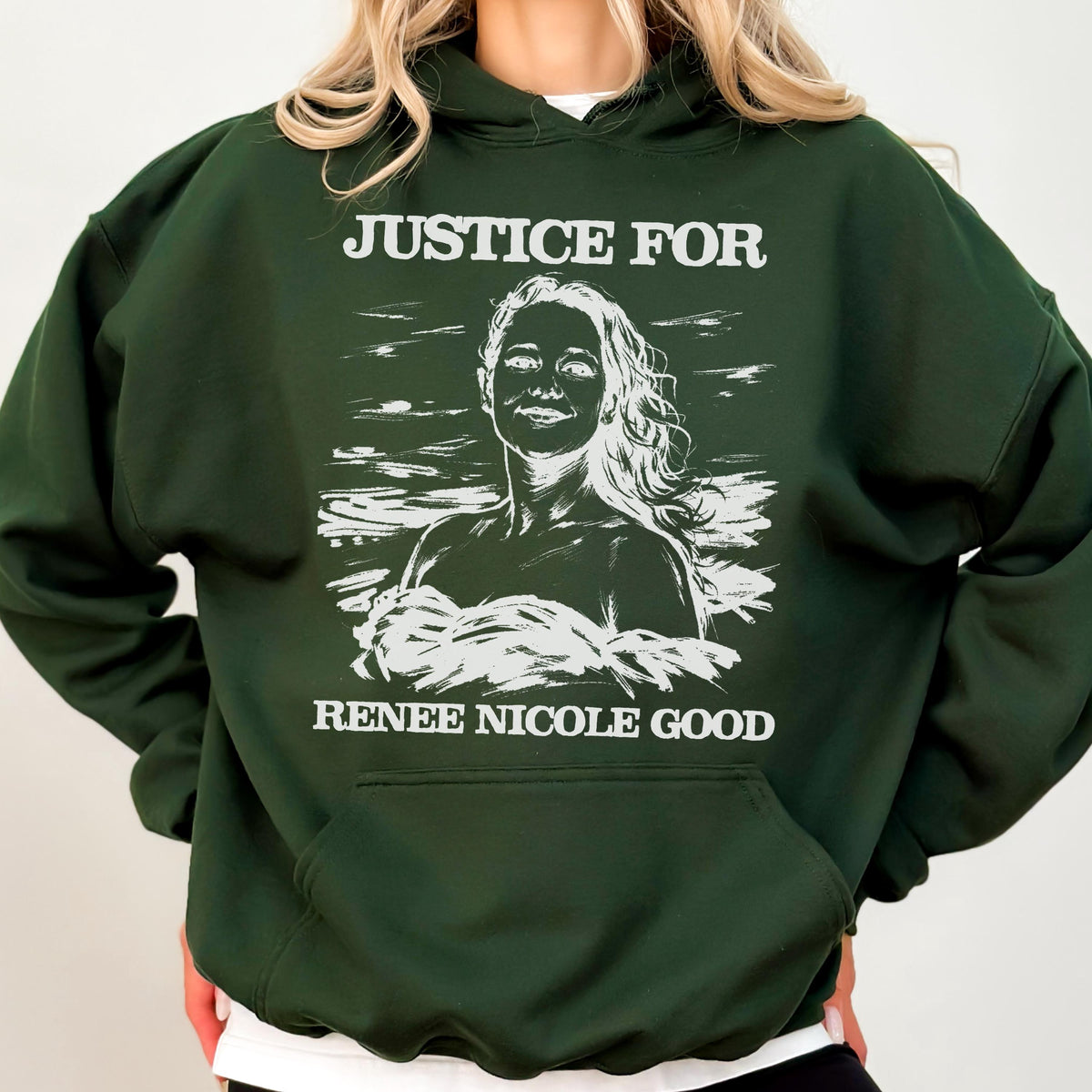 May include: A dark green hoodie with a white graphic that reads "JUSTICE FOR" above a portrait of a woman and "RENEE NICOLE GOOD" below. The hoodie has a hood and a front pocket.