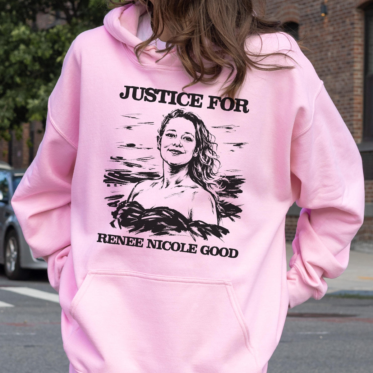 May include: A light pink hoodie with a front pocket and a hood. The back of the hoodie features a black and white graphic of a woman with the text "JUSTICE FOR" above and "RENEE NICOLE GOOD" below the image.