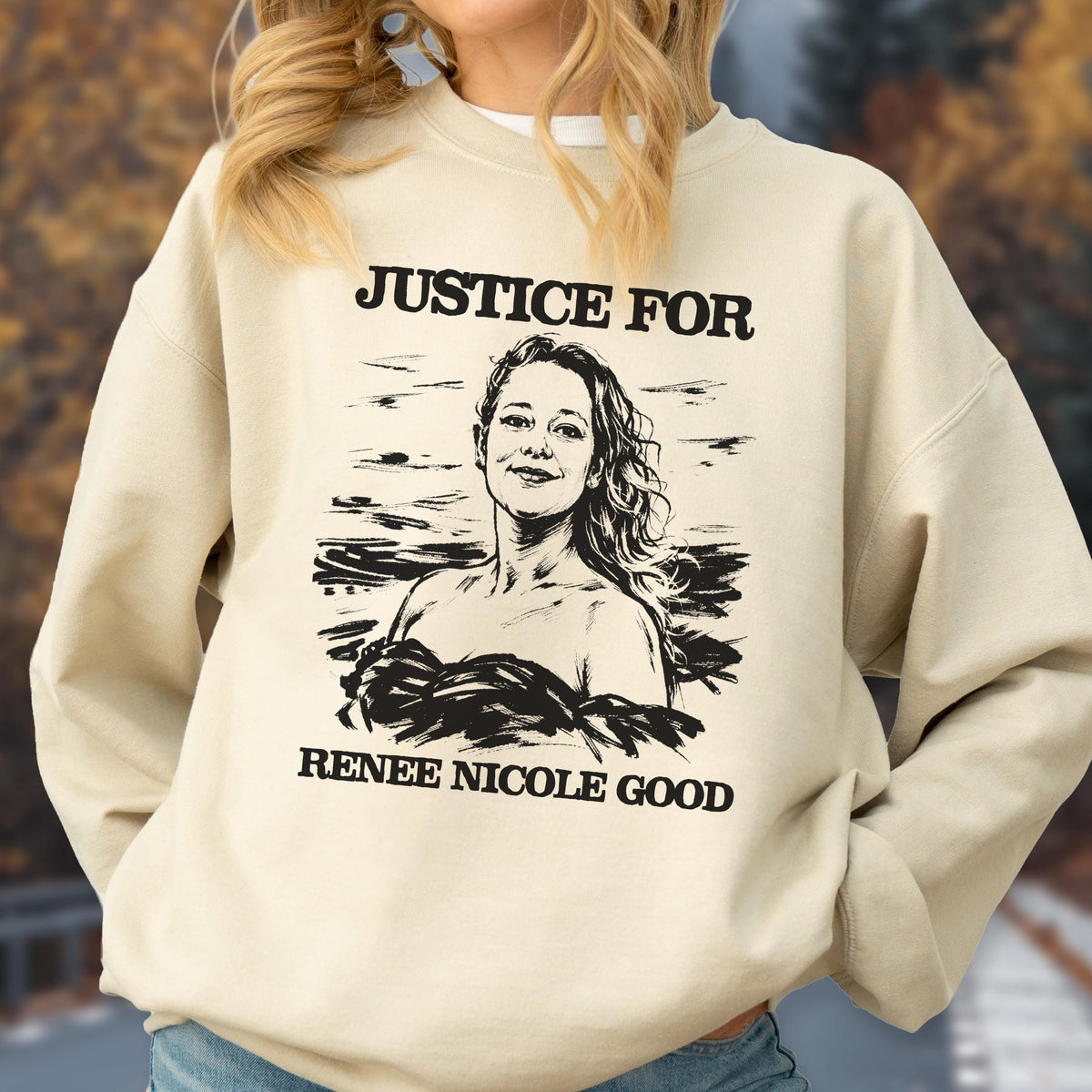 May include: A beige sweatshirt with the text "JUSTICE FOR" above a black and white portrait of a woman, with the text "RENEE NICOLE GOOD" below the portrait. The sweatshirt is a neutral color.