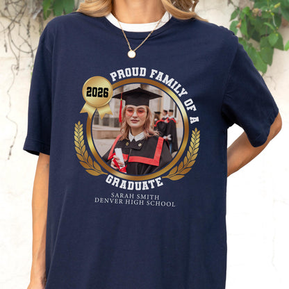 May include: Navy blue t-shirt with a graduation-themed design. The design includes a photo of a graduate, the text "Proud Family of a Graduate," the year 2026, and the graduate's name and high school.