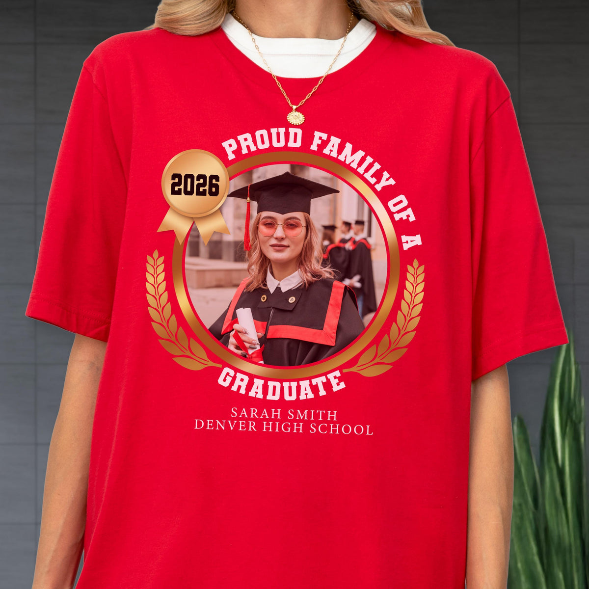 May include: Red t-shirt with a graduation design. The design includes a photo of a graduate in a cap and gown, the words "Proud Family of a Graduate," the year "2026," and the graduate's name and high school.