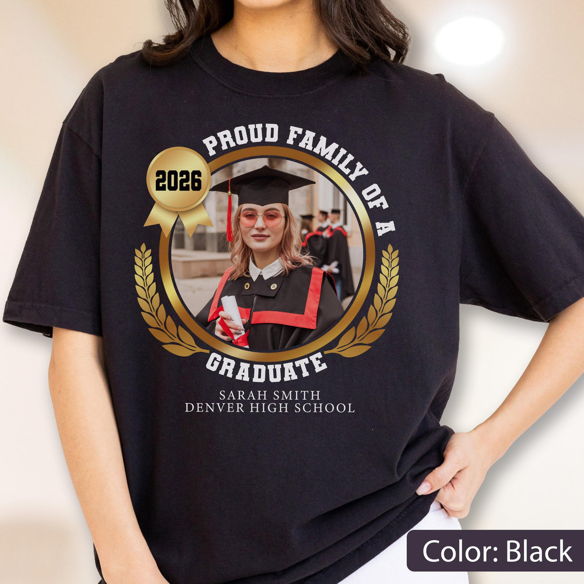 May include: Black t-shirt with a gold emblem featuring a graduate's photo, the text "Proud Family of a Graduate," and the year "2026." The graduate's name and high school are printed below. The shirt is a graduation-themed apparel.