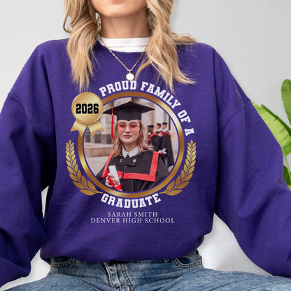 May include: A purple sweatshirt with a graduation-themed design. The design includes a photo of a graduate, the text "PROUD FAMILY OF A GRADUATE", the year "2026", and the graduate's name and high school.