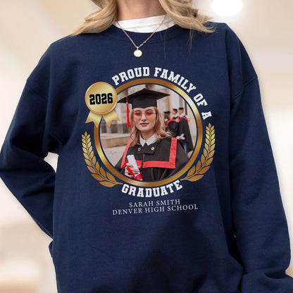 May include: Navy blue sweatshirt with a gold emblem featuring a graduate's photo, the year 2026, and the text "Proud Family of a Graduate." The graduate's name and high school are also displayed.