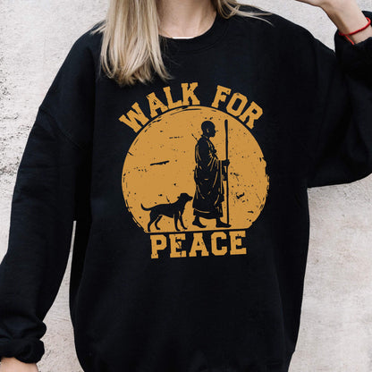 May include: Black sweatshirt with a golden-yellow graphic. The graphic features a figure with a staff, a dog, and the words "WALK FOR PEACE" in a circular design. The sweatshirt is a crew neck style.