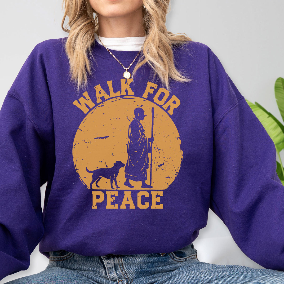 May include: A purple sweatshirt with a circular graphic featuring a figure with a dog and the words "WALK FOR PEACE" in a distressed style. The graphic is in shades of orange and brown.