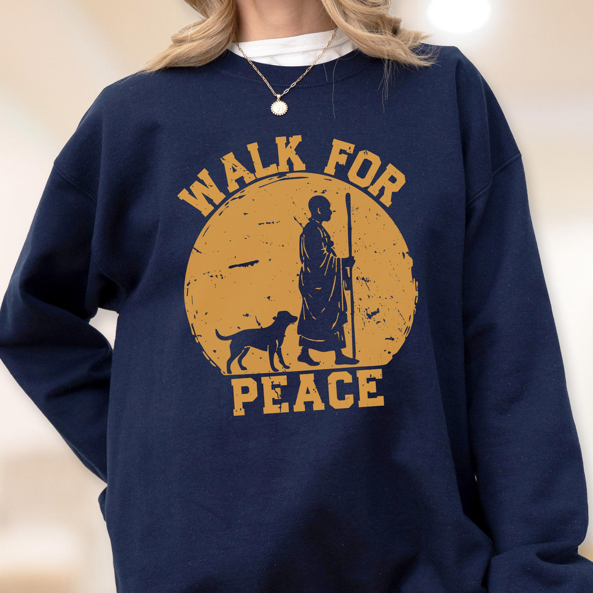 May include: Navy blue sweatshirt with a distressed gold graphic. The graphic features a figure with a staff, a dog, and the words "WALK FOR PEACE" in a circular design. The sweatshirt is a crew neck style.