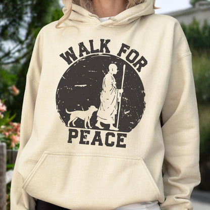 May include: A beige hoodie with a front pocket and a drawstring hood. The front features a distressed black graphic of a person with a dog and the words "WALK FOR PEACE" in a circular design.