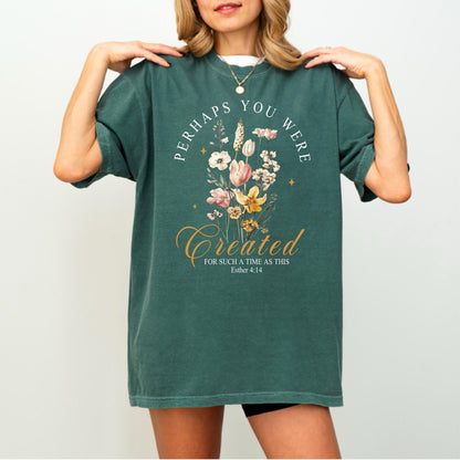 May include: Green t-shirt with the text "PERHAPS YOU WERE CREATED FOR SUCH A TIME AS THIS" and a floral bouquet design. The design includes white, pink, and yellow flowers. The shirt is a casual, oversized fit.