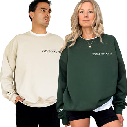 May include: A beige crewneck sweatshirt with the black Roman numeral text XXX-I-MMXXVI on the chest and M with a heart on the sleeve, alongside a dark green crewneck sweatshirt with the same text and R with a heart on the sleeve.